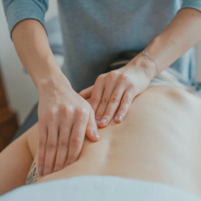 2 hands massaging person's back